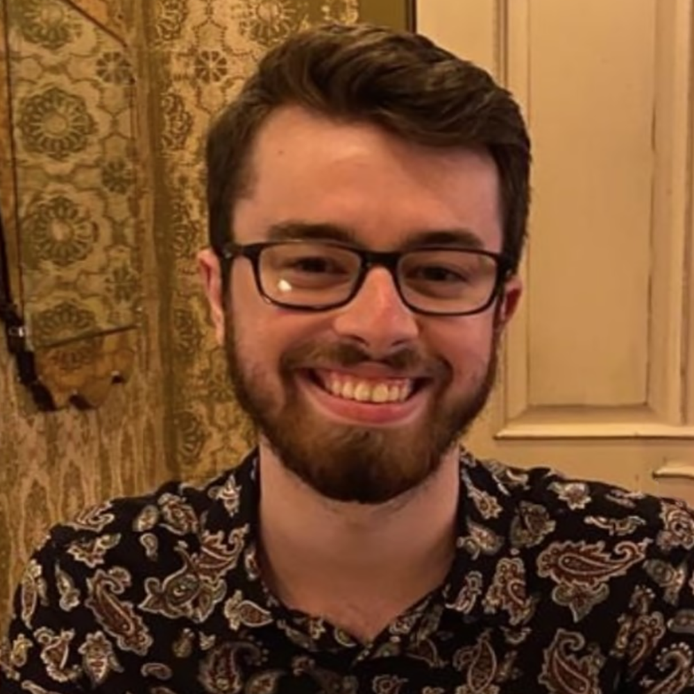 Headshot of Jack Bennett. He is wearing a paisley shirt and glasses and is smiling to the camera.