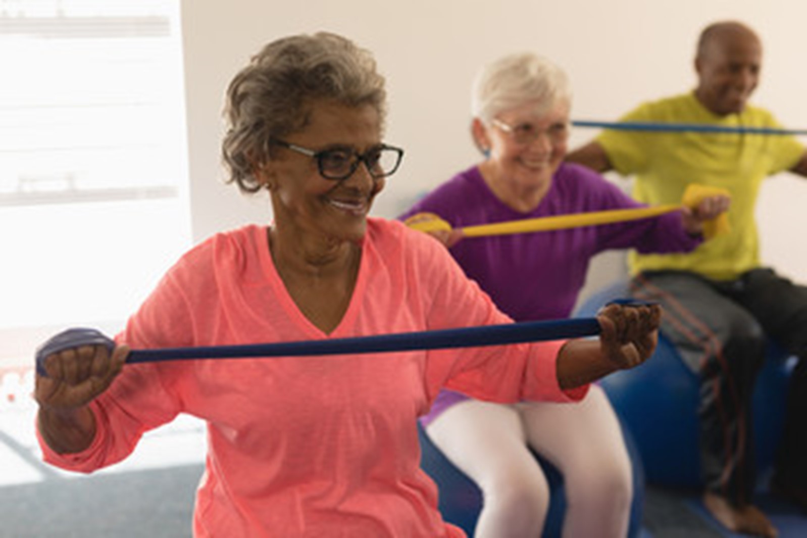 Row of elderly people holding exercise bands in an exercise class