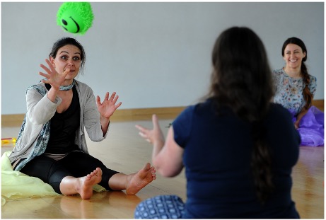 Movement group, people performing ball moves whilst sitting down on the floor in a room