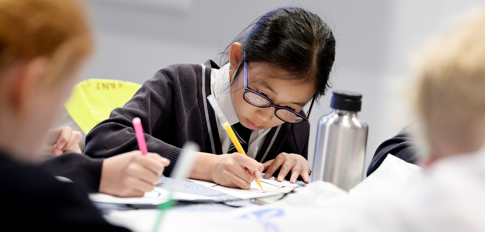 A school pupil holding a felt tip pen at a desk and working