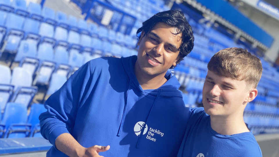 Volunteer and student in front of seating at Everton FC ground