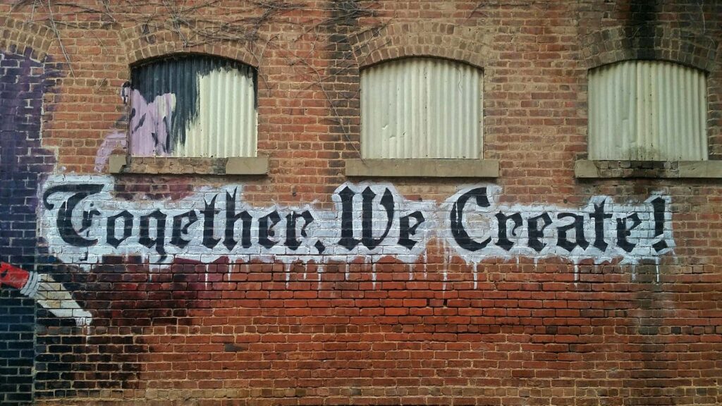 Graffiti on a brick wall that reads: 'Together, we create!'