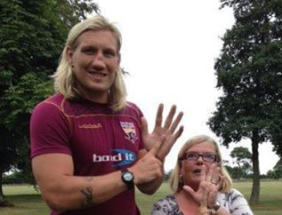 Two people including a professional rugby player performing the "one-in-five" hand gesture, with the index finger of one hand presented in front of the open palm of the other.