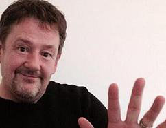 Johnny Vegas performing the "one-in-five" hand gesture, with the index finger of one hand presented in front of the open palm of the other.