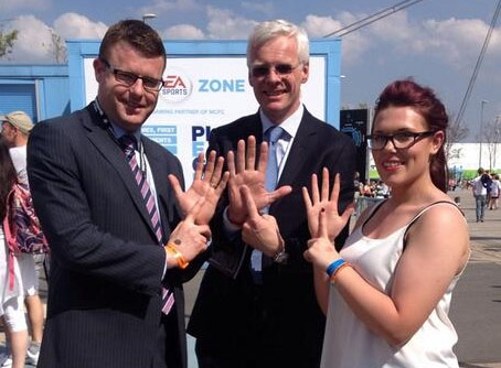 A group of people performing the "one-in-five" hand gesture, with the index finger of one hand presented in front of the open palm of the other.