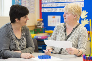 A teacher abd teaching assistant discussing a lesson plan together