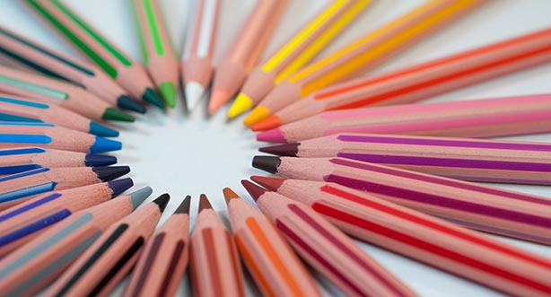 Photo by Agence Olloweb on Unsplash, wooden multi-coloured pencils arranged liying flat in a circle.