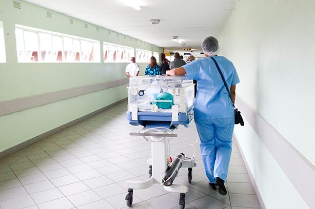 Hospital hallway, incubation unit being wheeled down a corridor by a nurse - pic by Jade Photography on Unsplash