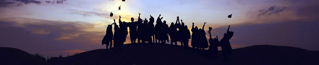 Photo by Baim Hanif on Unsplash, students on top of a hill during sunset, wearing graduate gowns