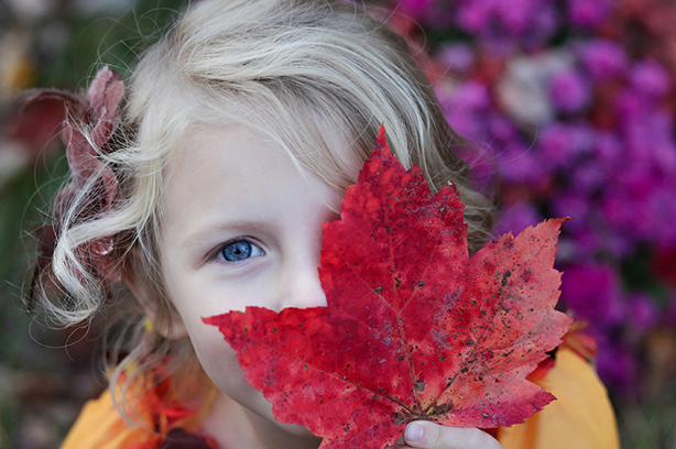 Photo by Gabby Orcutt on Unsplash, blond girl holding a red leaf infront of her face