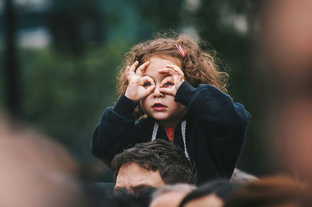Photo by Edi Libedinsky on Unsplash, girl on adults shoulders making glasses sign with hands