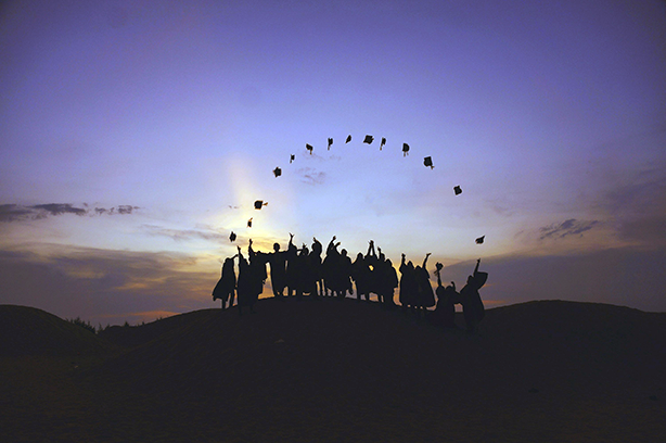 Photo by Baim Hanif on Unsplash, students on top of a hill during sunset, wearing graduate gowns