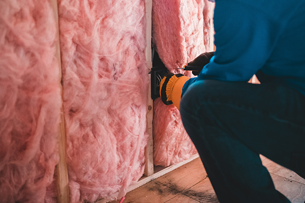 Photo by Erik Mclean on Unsplash, man adding insulation to a home