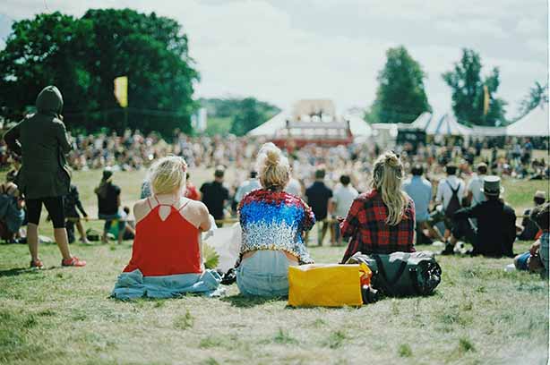 Photo by Aranxa Esteve on Unsplash, women sitting in the sun at a music festival