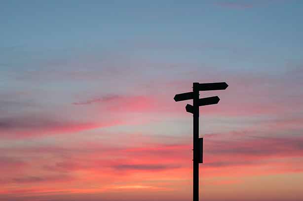 Photo by Javier Allegue Barros on Unsplash, signpost silhouette against a pink sky