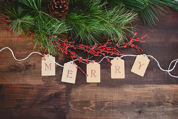 Photo by Debby Hudson on Unsplash, 'merry' word on a wooden table with a pine branch