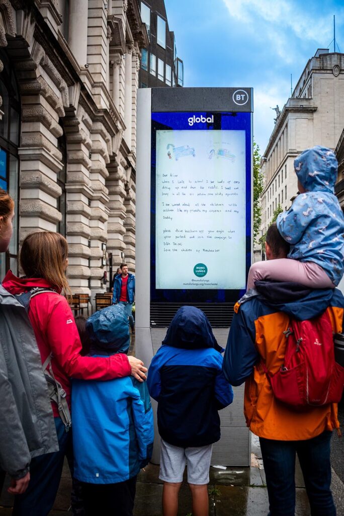 Passers by looking at Mums for Lungs street advertising board in central Manchester - copyright Mums for Lungs