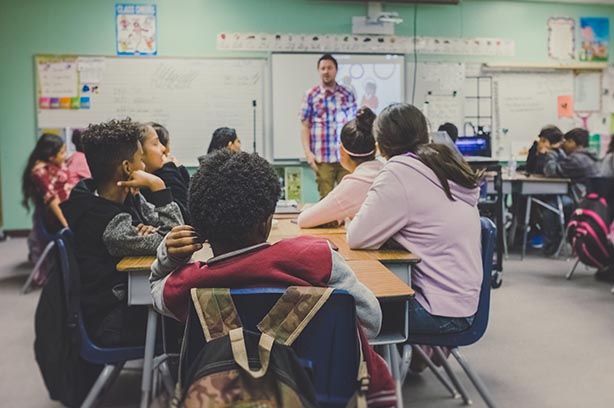 School classroom, children sitting at desks listening to their teacher - pic by Kenny Eliason on UnSplash