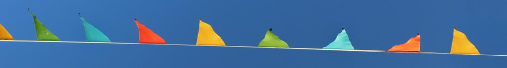 Blue sky with multiple multy coloured flags on a ribbon.