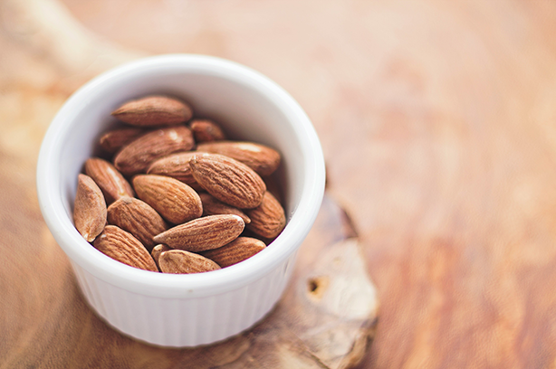 Photo by Juan José Valencia Antía on Unsplash, almonds in a bowl on a wooden surface