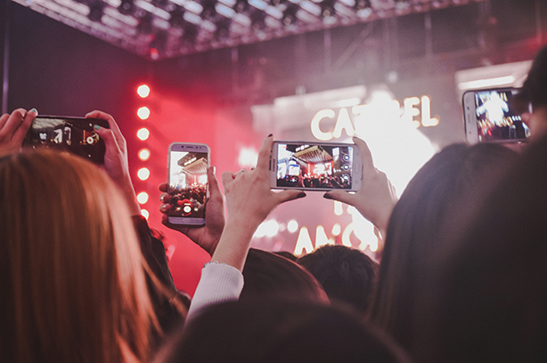 Photo by Noralí Nayla on Unsplash, not watching the concert, using smart phones to record or take photos instead