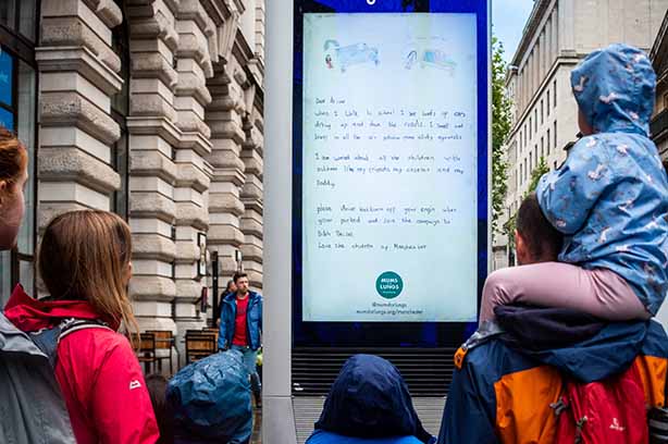 Passers by looking at Mums for Lungs street advertising board in central Manchester - copyright Mums for Lungs