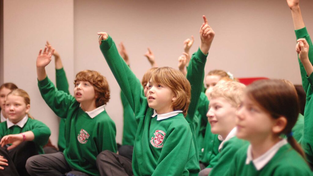 A group of primary school students put their hands up to answer a question