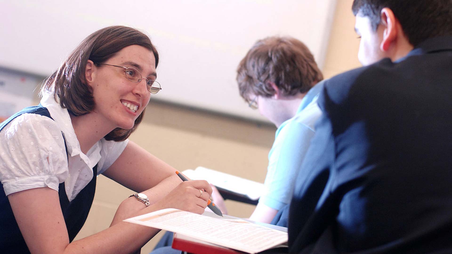 A tutor helps a secondary school student with work,