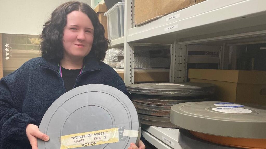 Archives apprentice Aimy Stevens holding a reel in the archives 