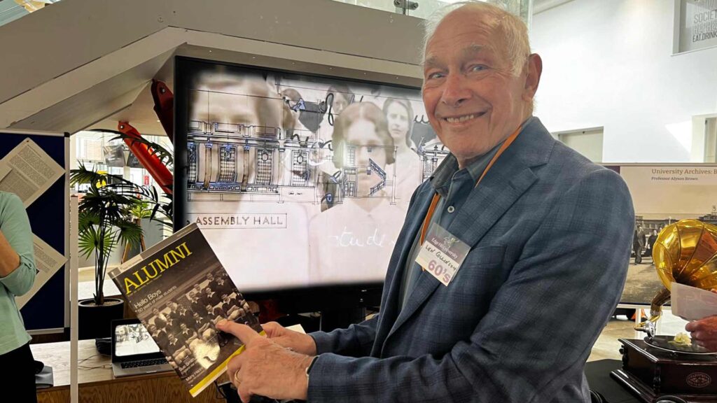 Len Colinson holding a old photograph of students
