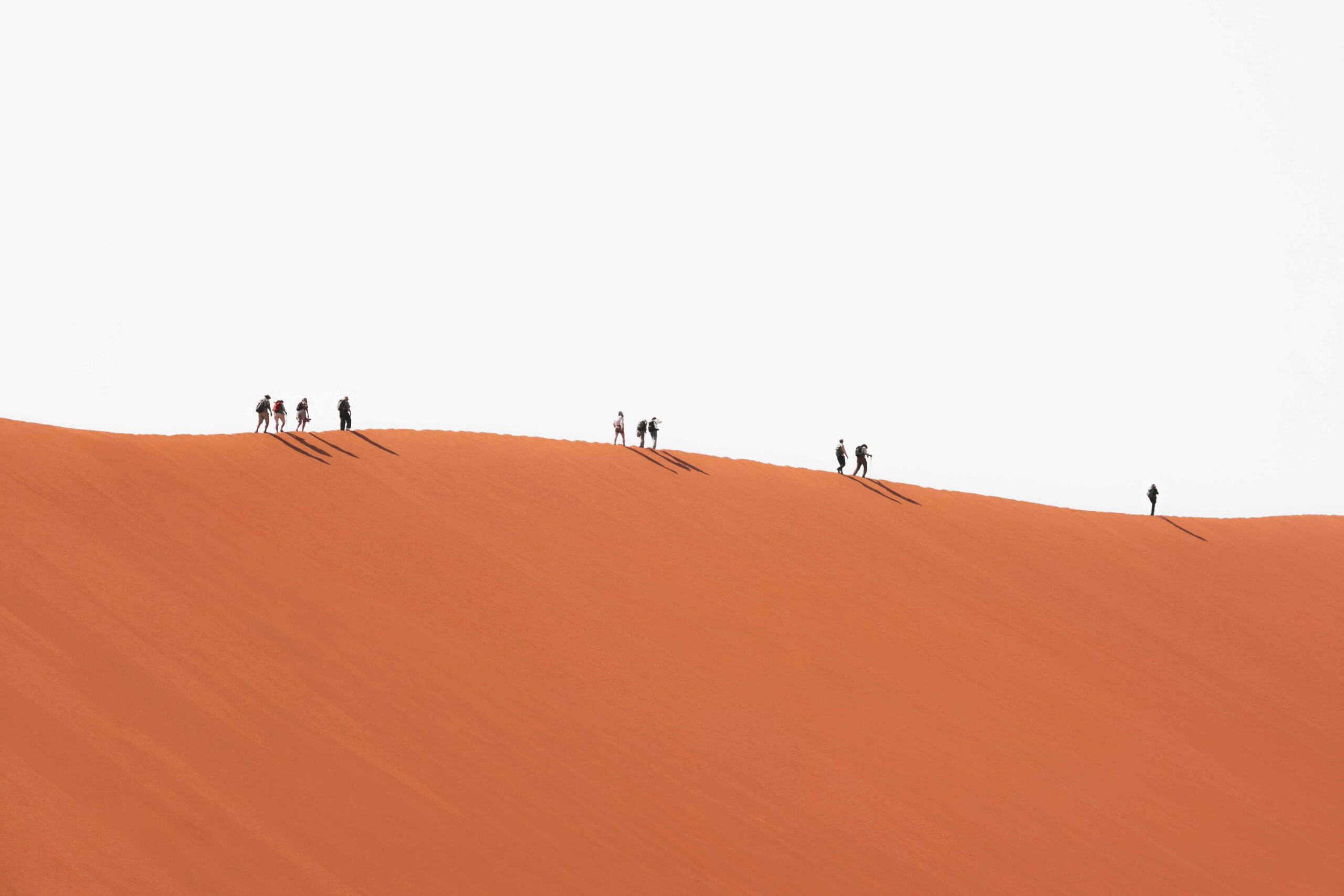 Photo by Joshua Kettle on Unsplash, a group of people walking on a sand dune
