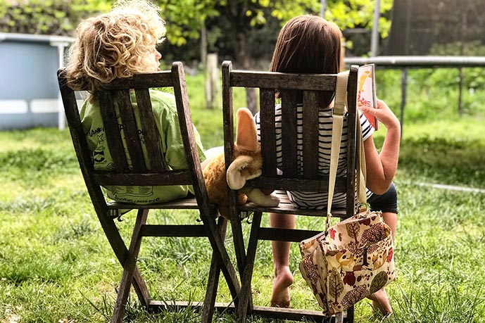 Children sitting on deck chairs in a garden