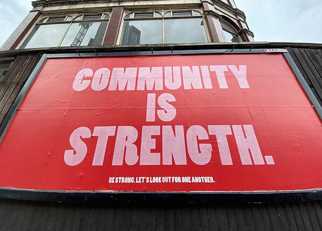 Large public billboard saying 'community is strength'