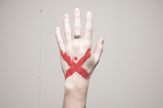 Hand with a red cross painted on it to depict modern slavery