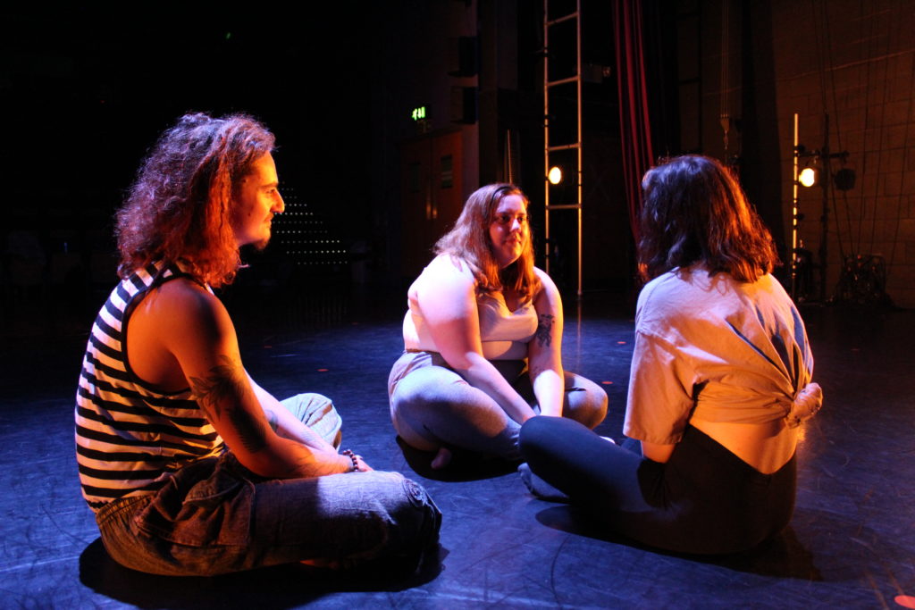 Tenderfoot theatre actors sitting on the floor cross legged in a circle