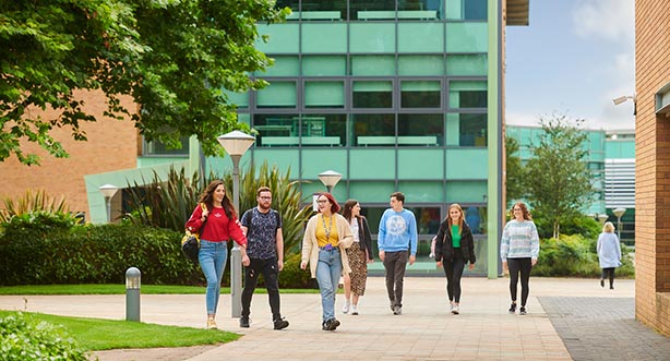Two groups of students walking around the campus, 3 on left side and 4 the right.