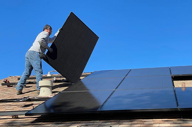 man fitting sun panels onto a roof