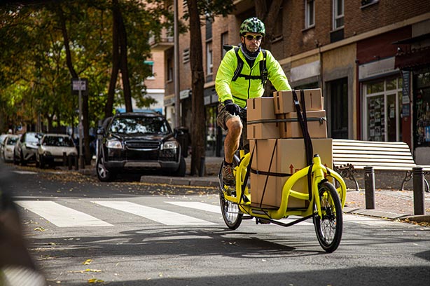 courier traveling with his cargo bike through the city, side view