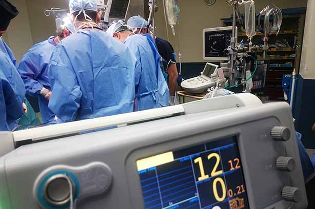 Photo by Natanael Melchor on Unsplash, surgeons performing and operation, heart monitor in the foreground