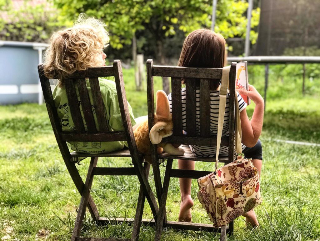 Children sitting on deck chairs in a garden