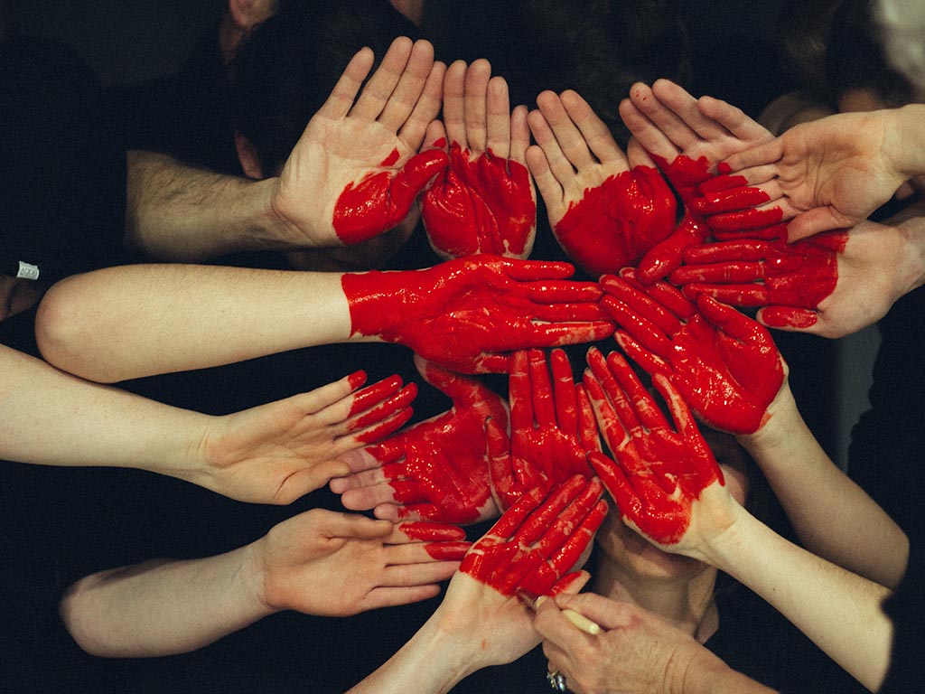Many hands facing outwards and painted to create a heart