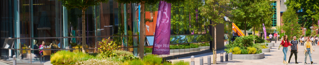 Three students walking infront of the HUB taken from outside looking past some large flags