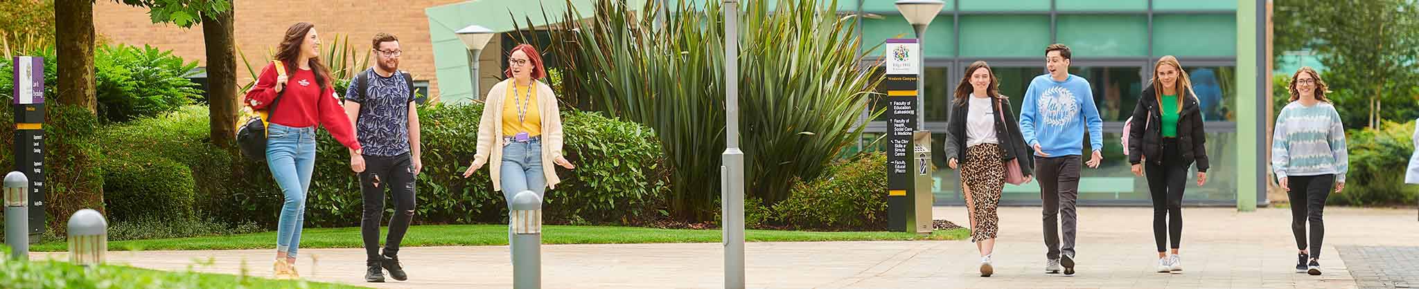 Two groups of students walking around the campus, 3 on left side and 4 the right.