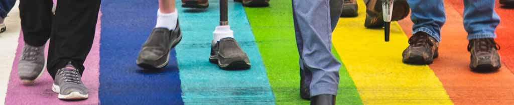 Feet walking across a rainbow pedestrian crossing