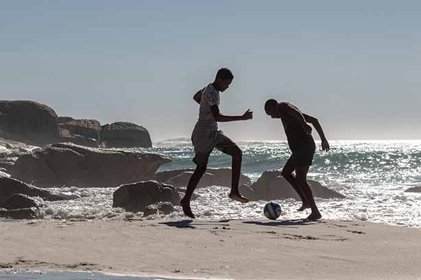 Photo by Grant Durr on Unsplash, two men playing with football near the seashore