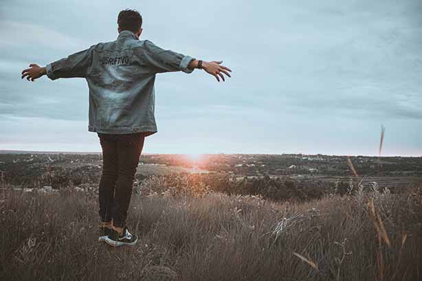 Photo by DISRUPTIVO on Unsplash, man standing in a field with arms outstretched